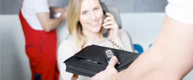 egy nő mobiltelefonál, miközben egy pénztárcát tart a kezében